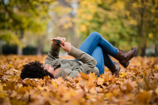 Teen girl using her mobile while lying in the park