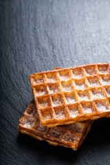 Food concept Classic square Waffles with icing sugat toping on black slate stone board