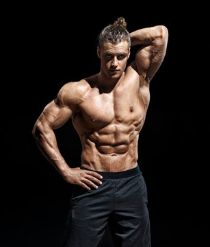 Handsome athletic man posing. Photo of young guy with perfect physique on black background. Strength and motivation