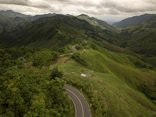 Aerial view of countryside road passing through the lush greenery and foliage tropical rain forest mountain landscape in the Northern Thailand