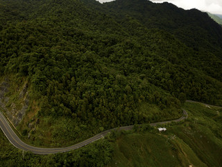 Fototapeta na wymiar Aerial view of countryside road passing through the lush greenery and foliage tropical rain forest mountain landscape in the Northern Thailand