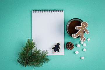 Christmas mock up blank greeting card. Fir tree branches, cup with cocoa, gingerbread and decorations over green paper background. Flat lay. Top view. Copy space