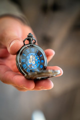 The pocket watch in noble blue, is held in the hand