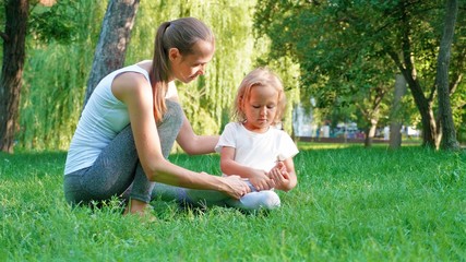 Naklejka na ściany i meble Young sporty mother coaching her little cute daughter doing yoga exercise