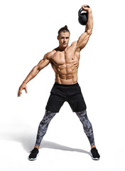 Young muscular guy training with kettlebell. Photo of handsome man with naked torso on white background. Strength and motivation. Full length