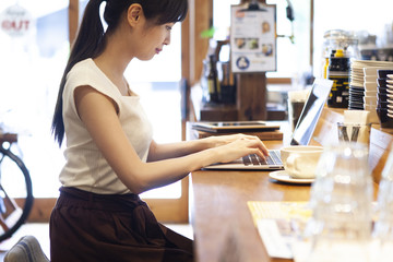 カフェのカウンターでPC作業に集中する女性