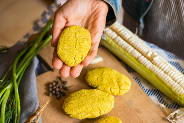 Woman hand holds Mchadi - traditional white corn flour Georgian bread with turmeric powder. Samegrelo region cornbread. Vegan crusty bread, vegetarian healthy food.