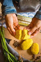 Woman hand break into halves Mchadi - traditional white corn flour Georgian bread with turmeric powder. Samegrelo region cornbread. Vegan crusty bread, vegetarian healthy food.