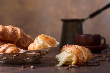 Fresh and tasty croissant  and cup of coffee on old copper background.