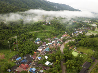 Aerial view of a village in the lush green rain cloud cover tropical rain forest mountain during...