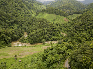 Aerial view of a village in the lush green rain cloud cover tropical rain forest mountain during...