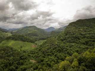 Aerial view of a village in the lush green rain cloud cover tropical rain forest mountain during...