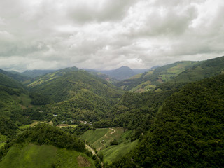 Aerial view of a village in the lush green rain cloud cover tropical rain forest mountain during...