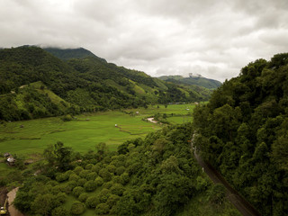 Aerial view of a village in the lush green rain cloud cover tropical rain forest mountain during...