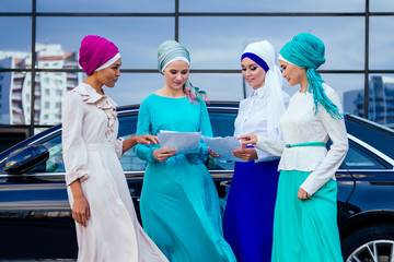 group of four successful business multinational Muslims women in stylish veiled hijab a turban...