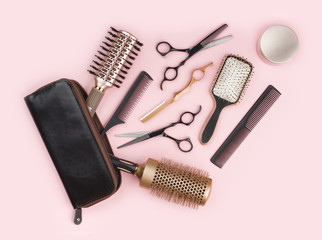 Hair dresser tool set with leather bag on pink background