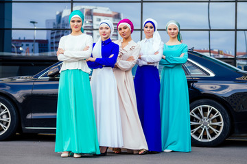 group of five strong beautiful and young Muslim business women fashion look stylish long dress and the turban covers the head standing powerful proudly ,car and skyscraper street background