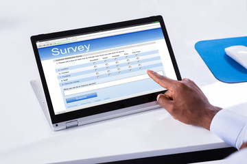 Businessman's Hand Filling The Survey Form On Laptop