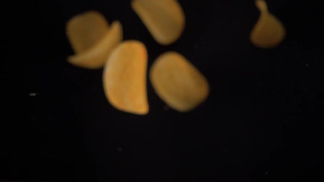 Potato chips flying up on black background. The view from the top. Pringles. Lays