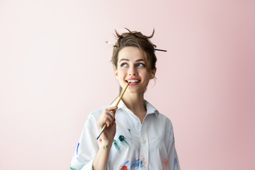Beautiful young woman biting brush in happy dreams - obrazy, fototapety, plakaty