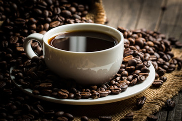 Coffee cup and beans on a rustic background. Coffee Espresso and a piece of cake with a curl. Cup of Coffee and coffee beans on table.