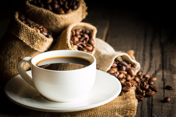 Coffee cup and beans on a rustic background. Coffee Espresso and a piece of cake with a curl. Cup of Coffee and coffee beans on table.
