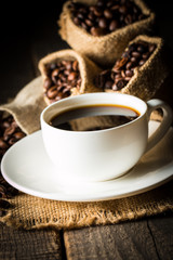 Coffee cup and beans on a rustic background. Coffee Espresso and a piece of cake with a curl. Cup of Coffee and coffee beans on table.