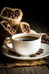 Coffee cup and beans on a rustic background. Coffee Espresso and a piece of cake with a curl. Cup of Coffee and coffee beans on table.