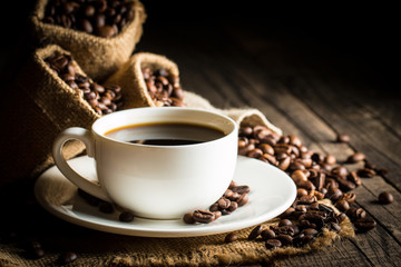 Coffee cup and beans on a rustic background. Coffee Espresso and a piece of cake with a curl. Cup of Coffee and coffee beans on table.