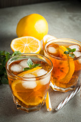 Glasses of cold ice tea with lemon, ice, mint on background. Homemade lemonade. Spring and summer drinks and beverages concept. 