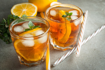 Glasses of cold ice tea with lemon, ice, mint on background. Homemade lemonade. Spring and summer drinks and beverages concept. 