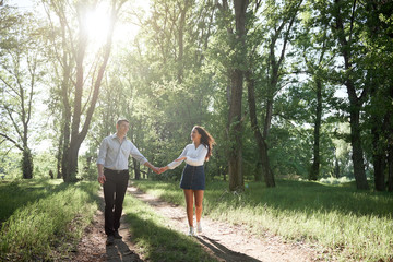young couple walking in the forest, summer nature, bright sunlight, shadows and green leaves, romantic feelings