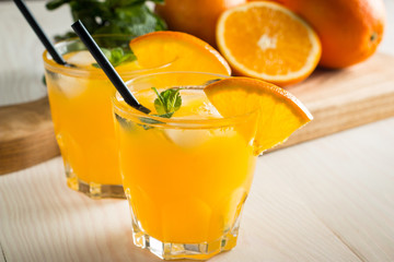 Photo of fresh orange juice in the glass jar. Summer healthy organic drink concept. Cold beverages with ice and orange fruits.
