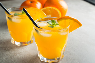 Photo of fresh orange juice in the glass jar. Summer healthy organic drink concept. Cold beverages with ice and orange fruits.