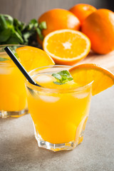 Photo of fresh orange juice in the glass jar. Summer healthy organic drink concept. Cold beverages with ice and orange fruits.