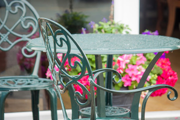Outside table and chairs with a floral background. 