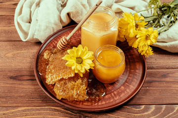 Obraz na płótnie Canvas Honey in jar with honey dipper on vintage wooden background