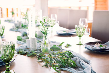 Wedding. Banquet. Table for guests, covered with a tablecloth, decorated with candles, transparent glass vases, fresh flowers