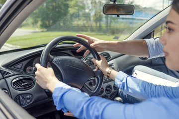 Driving School - Young woman steer a car with the steering wheel, maybe she has a driving test...