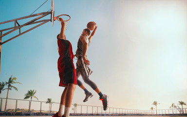 Streetball. Basketball player in action on sunset.