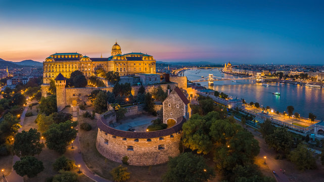 Budapest, Hungary - Aerial panoramic skyline view of beautiful illuminated Buda Castle Royal Palace with Szechenyi Chain Bridge, Hungarian Parliament at blue hour - Powered by Adobe