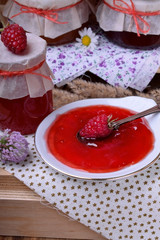 Red jam on a white plate. Jars of varying jam around