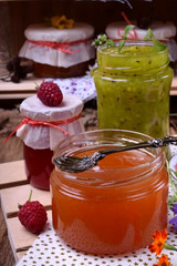 Orange, green and red jam in glass jars. Village interior
