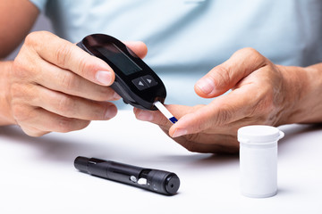 Man Checking Blood Sugar Level With Glucometer