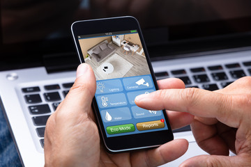 Man Holding Cellphone With Home Control System