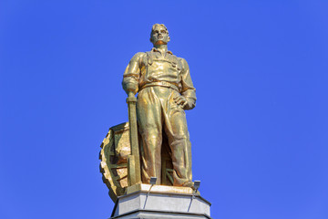 Fototapeta na wymiar Figure of man tractor driver on a roof of pavilion Space on VDNH in Moscow on a blue sky background in sunny summer morning