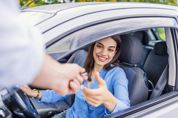 Fototapeta na wymiar Close up of young smiling woman getting keys of a new car. Concept for car rental