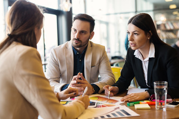 Three businesspeople in tense business meeting analyzing financial histograms.Team work in coffee shop. - Powered by Adobe