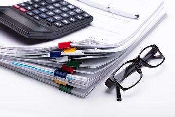 Close-up Of Calculator And Stacked Documents