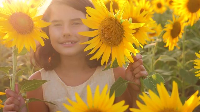 Happy portrait little girl on the field of sunflowers in summer. beautiful portrait little girl in sunflowers. slow motion video. girl lifestyle teenager and sunflowers field concept agriculture